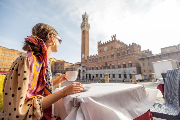 Frau beim Frühstück im Café im Freien mit schöner Aussicht auf den Hauptplatz der Stadt Siena Italien