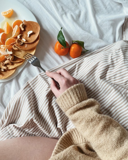 Frau beim Frühstück mit Pfannkuchen auf dem Bett