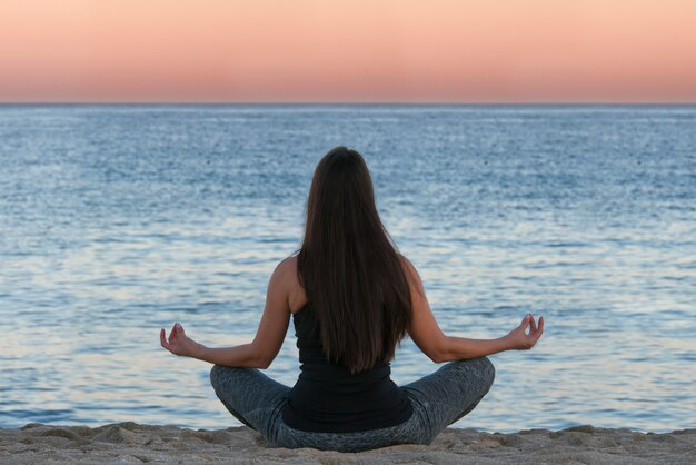 Frau beim Yoga und Meditation vor dem Meer