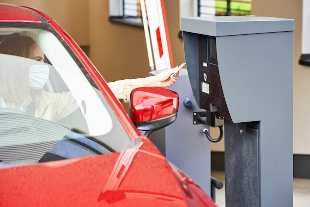 Frau bekommt Ticket von der Parkuhr in der Tiefgarage