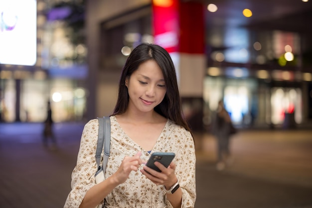 Frau benutzt das Handy in der Stadt am Abend