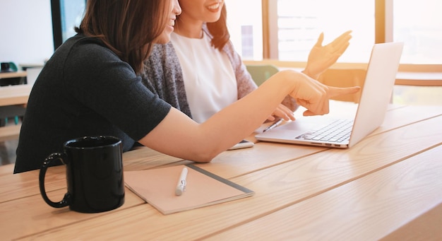 Frau benutzt das Telefon, während sie auf dem Tisch sitzt