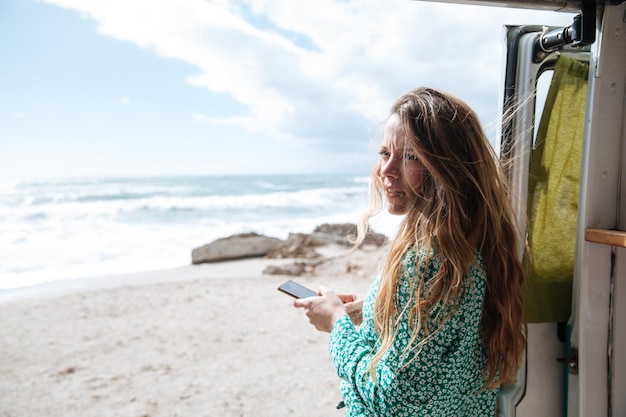 Frau benutzt ein Handy am Strand