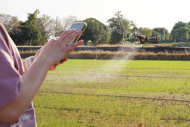 Frau benutzt ein Handy auf einem Bauernhof, umgeben von Landwirtschaftskontrollen Petrol Drone Sprayer