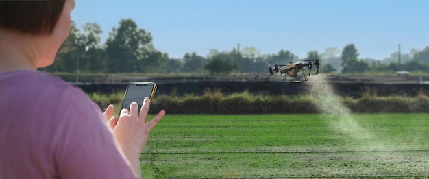 Foto frau benutzt ein handy auf einem bauernhof, umgeben von landwirtschaftskontrollen petrol drone sprayer