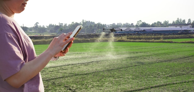 Foto frau benutzt ein handy auf einem bauernhof, umgeben von landwirtschaftskontrollen petrol drone sprayer