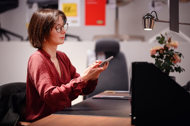 Frau benutzt ein Smartphone an einem modernen Büro-Schreibtisch