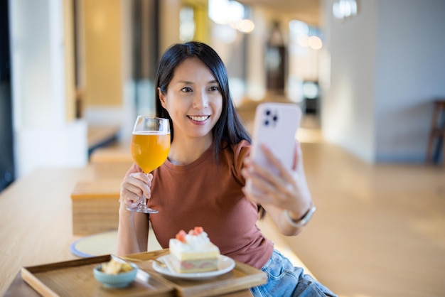 Frau benutzt Handy, um ein Selfie im Café zu machen