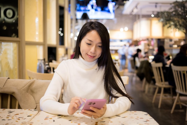 Frau benutzt Handy, um Essen im Restaurant zu bestellen