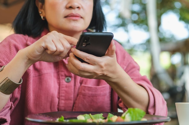 Foto frau benutzt handy und macht ein foto von salat, bevor sie im restaurant isst