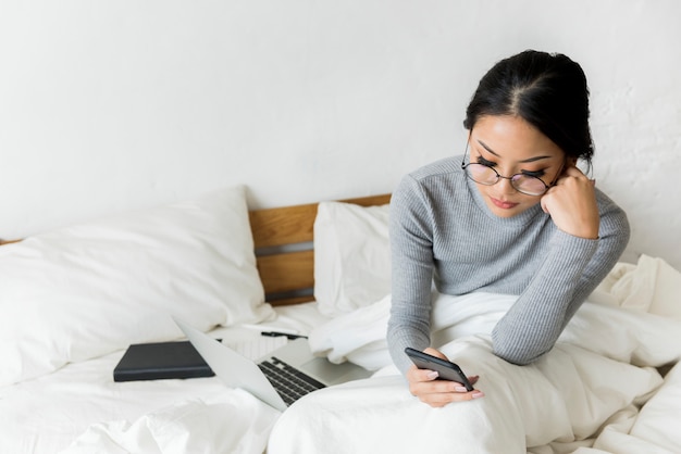 Frau benutzt Mobile auf dem Bett