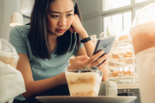 Frau benutzt Smartphone im Bäckerei-Café.