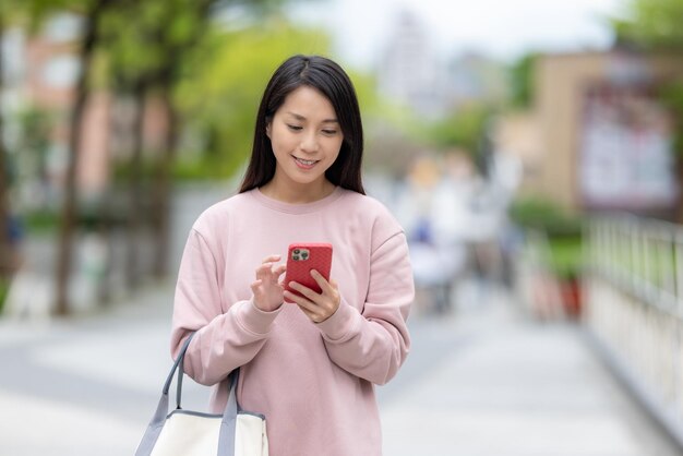 Frau benutzt Smartphone im Freien