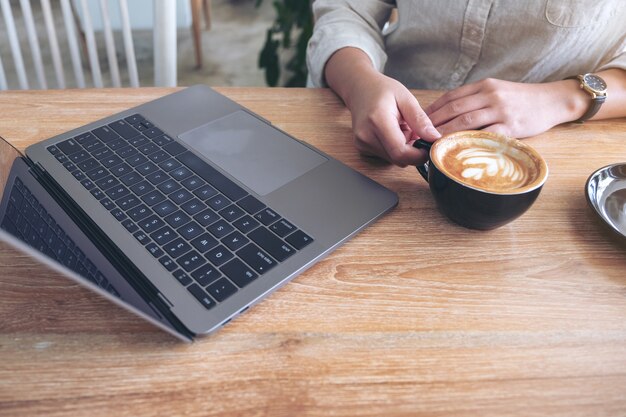 Frau benutzt und arbeitet am Laptop beim Kaffeetrinken