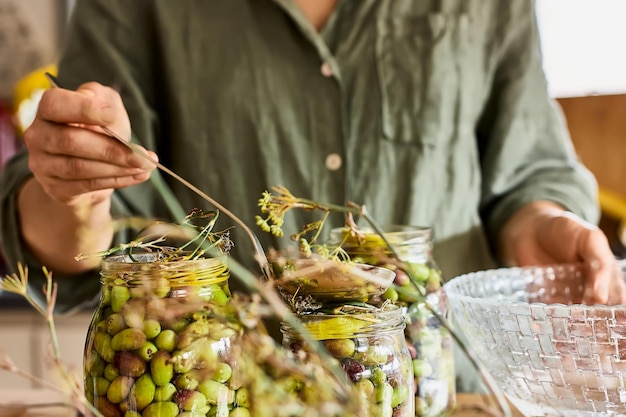 Foto frau bereitet fermentierte oliven in glasgläsern in der küche vor herbstgemüse in dosen