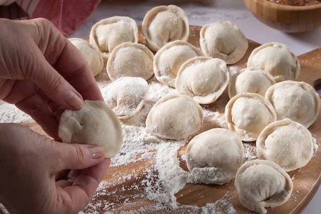 Frau bereitet hausgemachte klassische Knödel auf Holzbrett zu