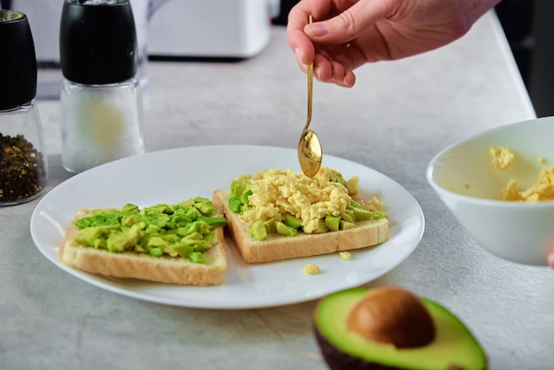 Frau bereitet Toast mit Avocado zu Gesunde Ernährung