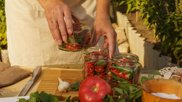 frau bereitet wintergetrocknete tomaten, gehackten knoblauch und frischen basilikum vor