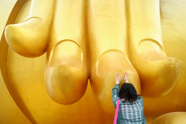 Frau berührt den Finger des großen Buddha-Bildes für den Segen im Tempel Wat Muang Thailand