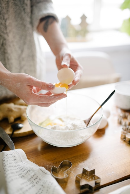 Frau bricht ein Ei und fügt dem Mehl hinzu. Prozess Kochen.