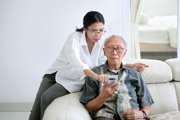 Frau bringt ihrem Vater bei, wie man ein Smartphone benutzt