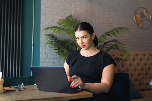 Frau Brünette arbeiten im Café mit Laptop und Kaffee