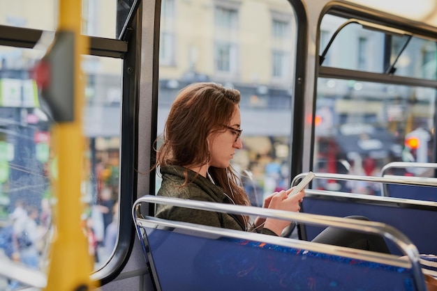 Frau Bus und Kopfhörer mit Telefon für SMS-Transport und Lesen mit sozialen Medien Person Musik und Smartphone zum Hören mit Audio-Streaming-Abonnement auf mobilen App für Pendeln