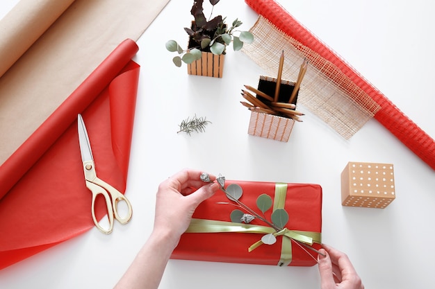 Frau dekoriert Geschenkbox auf dem Tisch