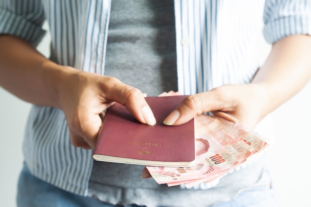 Frau der zufälligen Art, die Pass und thailändische Banknoten, Reisekonzept, Thailand-Tourist hält