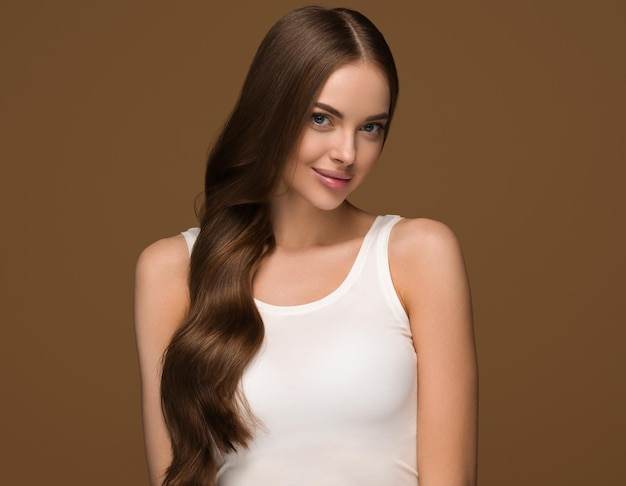 Frau des langen gesunden Haares mit langem gelocktem Haarschönheitshaut-Gesichtsporträt. Hintergrundfarbe braun