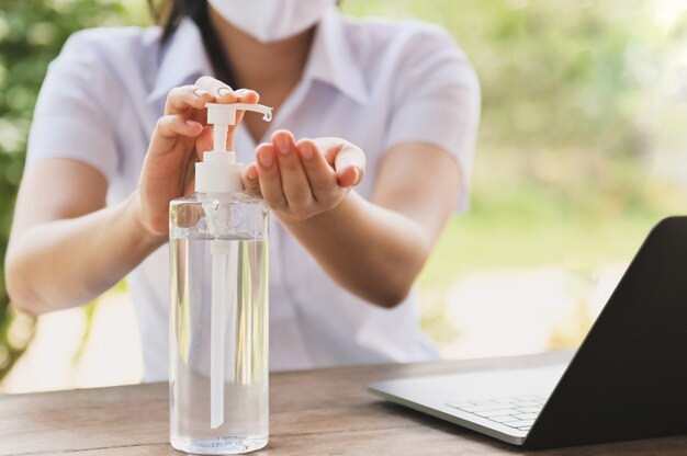 Frau, die Alkoholgel aus der Flasche verwendet und Desinfektionsmittel für Hand anwendet, machen Reinigungsvirus covid 19