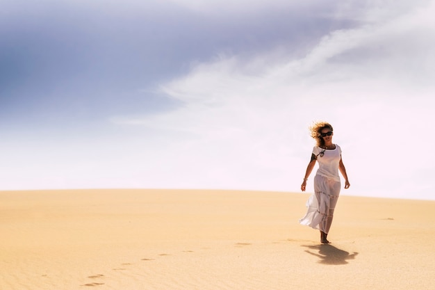 Frau, die allein in den Sanddünen der Wüste in der Freiheit Freizeitaktivität allein geht