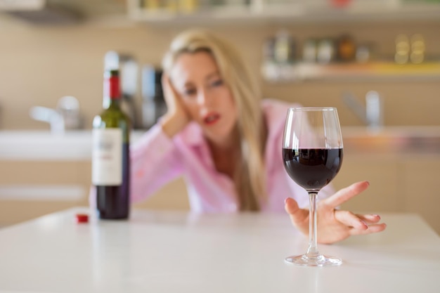 Frau, die allein zu Hause nach einem Glas Wein greift