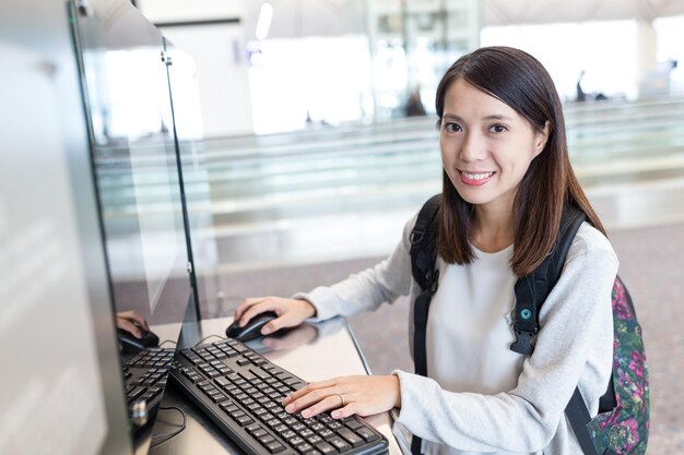 Frau, die am Flughafen am Computer sucht