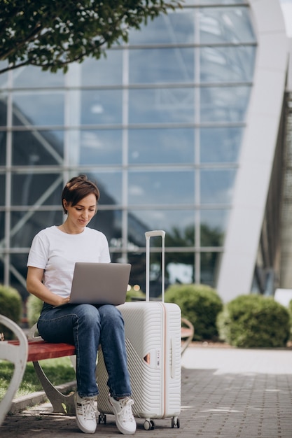 Frau, die am Flughafen reist und am Computer arbeitet