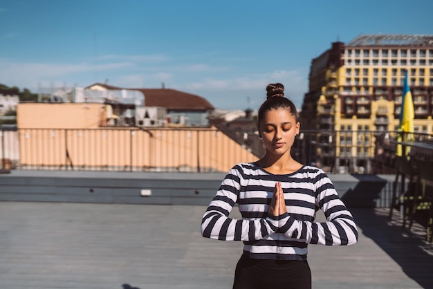 Frau, die am frühen Morgen Yoga-Übungen auf dem Hausdach macht