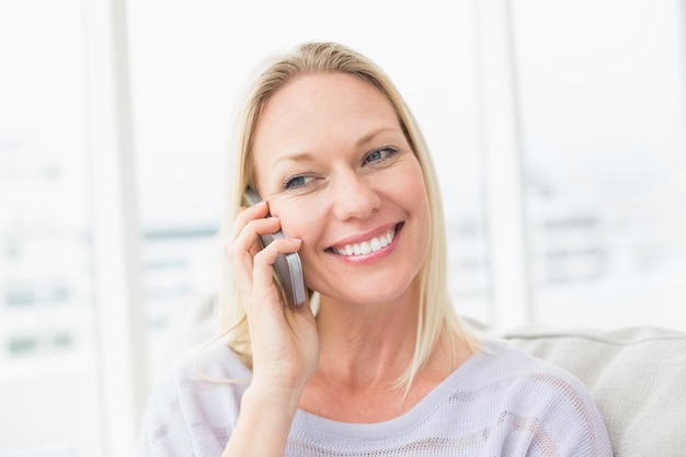 Frau, die am Handy im Wohnzimmer spricht