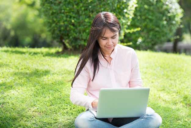 Frau, die am Laptop im Freien am Park arbeitet