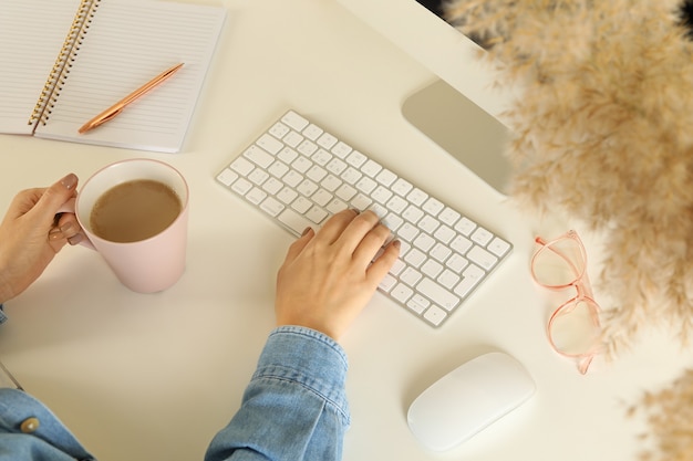 Frau, die am modernen Computer auf weißem Tisch arbeitet