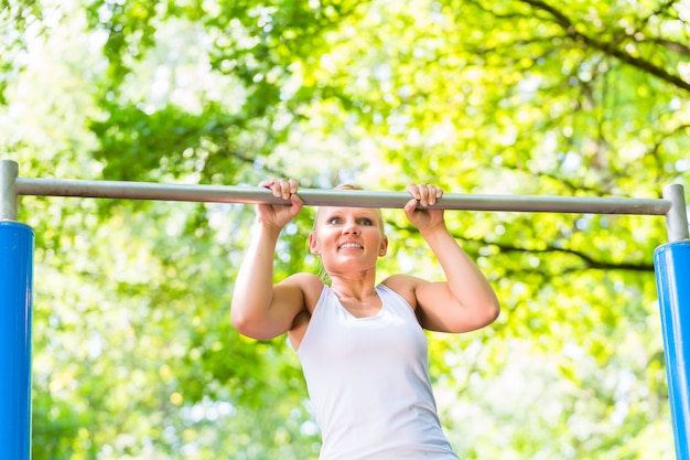 Frau, die am Reck für bessere Fitness im Freien trainiert