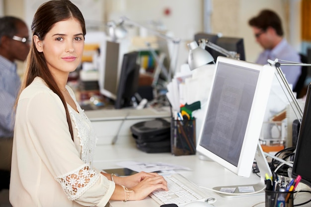 Frau, die am Schreibtisch im geschäftigen kreativen Büro arbeitet