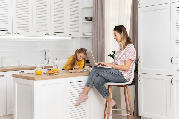 Foto frau, die am schreibtisch mit vollem schuss des mädchens arbeitet