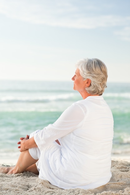 Frau, die am Strand sitzt