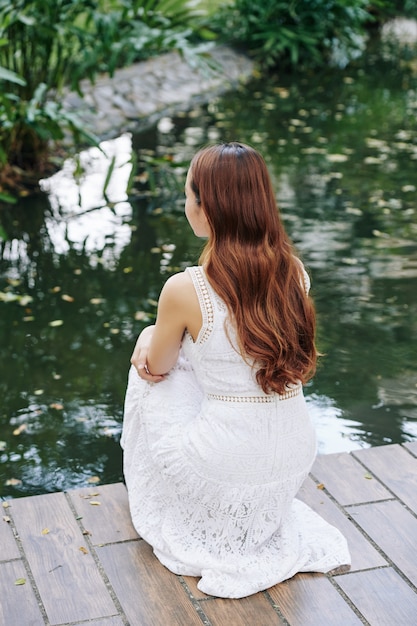 Frau, die am Teich im Park ruht