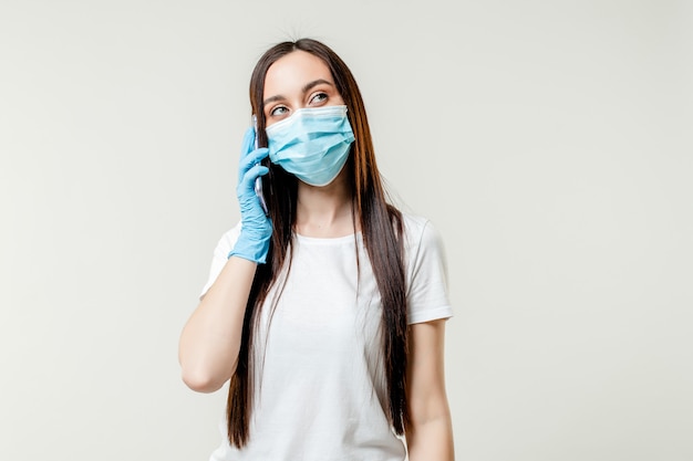 Foto frau, die am telefon mit maske und handschuhen spricht