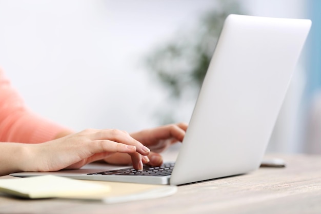 Frau, die am Tisch sitzt und mit Laptop arbeitet