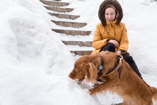 Foto frau, die am wintertag mit hund in der stadt spazieren geht und spielt
