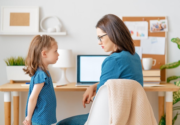 Frau, die an einem Laptop arbeitet. Lautes Kind und Fernarbeit von zu Hause aus.