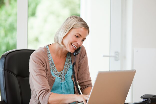 Frau, die an ihrem Computer arbeitet, während sie anruft