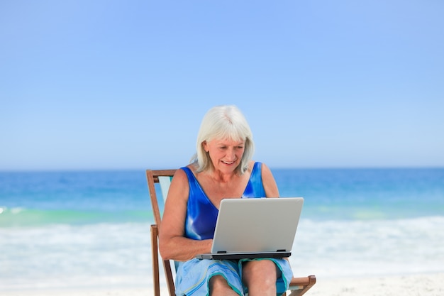 Frau, die an ihrem Laptop auf dem Strand arbeitet